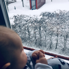 Unser Baby schaut aus dem Fenster in den Schnee