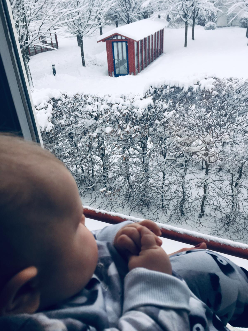Unser Baby schaut aus dem Fenster in den Schnee