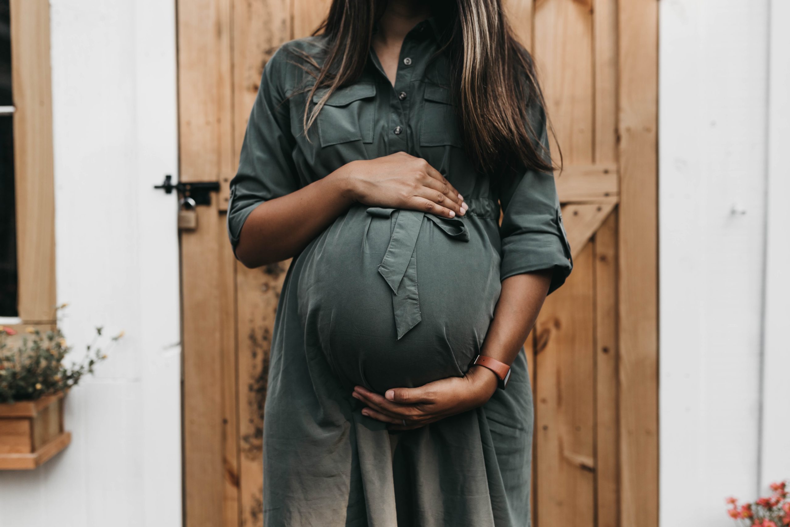 Eine schwangere Frau hält sanft ihren Babybauch