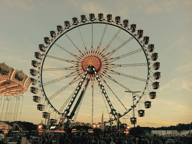 Das muenchner Riesenrad in seiner vollen Pracht bei Sonnenuntergang, unter ihm ist eine riesige Menschenmenge los.