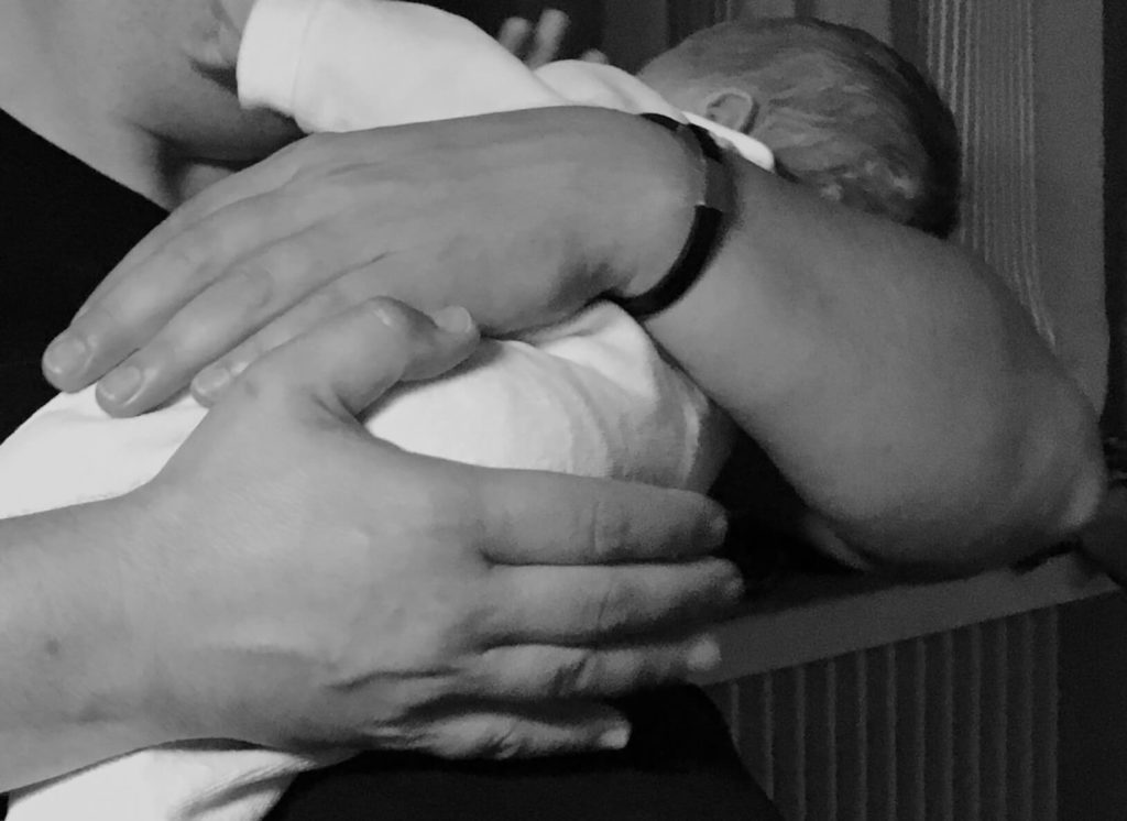 Frau hält Ihr ganz kleines Baby neugeboren im Arm
