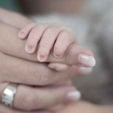 Finger eines Babys umfassen den Zeigefinger der Mama