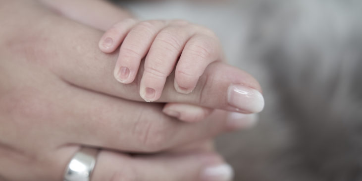Finger eines Babys umfassen den Zeigefinger der Mama