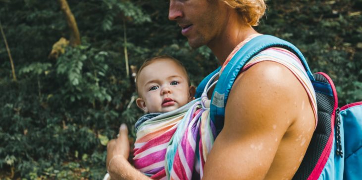 Baby in Trage und Vater mit Rucksack