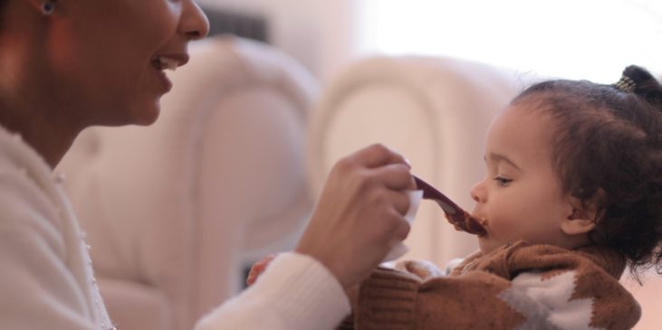 Mutter füttert Baby mit Löffel