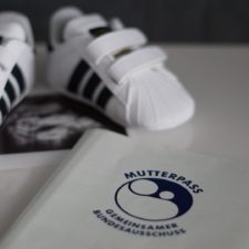 Babyturnschuhe neben einem Mutterpass