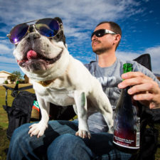 Ein junger Vater feiert mit alkohol-freiem Sangria und einem Hund auf seinem Schoss die Geburt seines Kindes