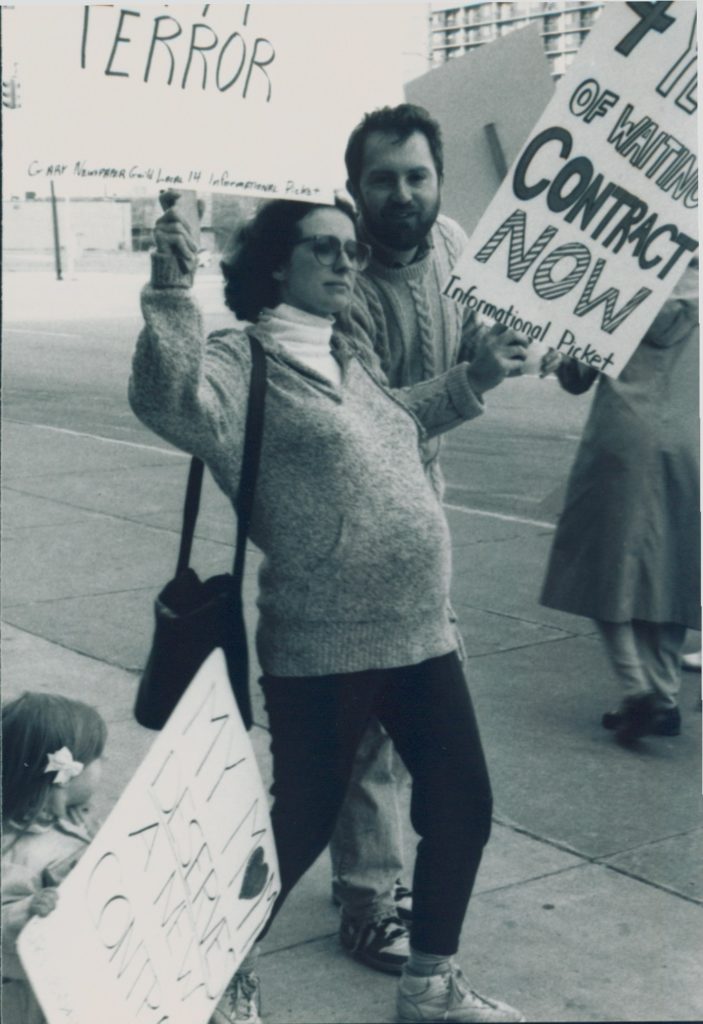 Eine schwangere Frau auf einer Demonstration hält Protestschilder hoch aus dem Jahr 1990