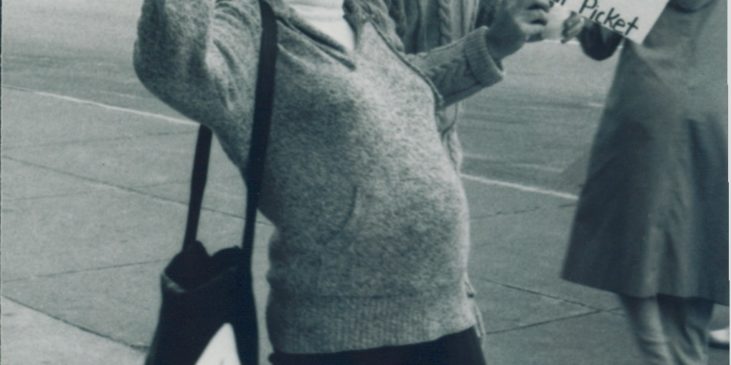 Eine schwangere Frau auf einer Demonstration hält Protestschilder hoch aus dem Jahr 1990
