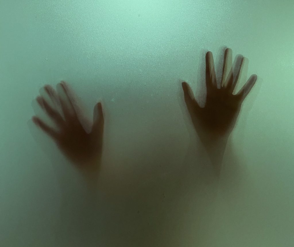 Zwei Hände an einer vernebelten Scheibe - ein Bild wie aus einem Alptraum